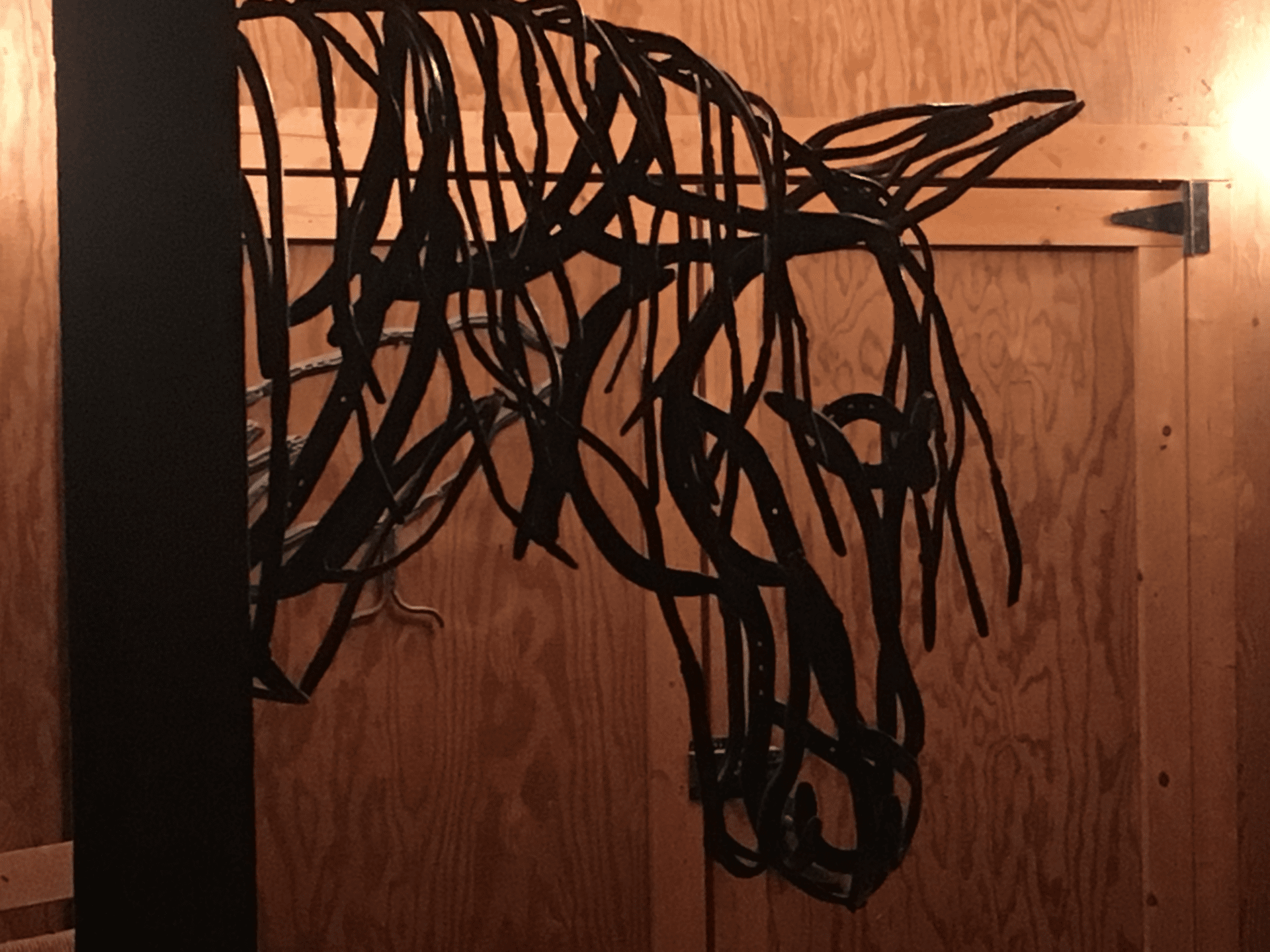 a horse head made of wire hanging from a door